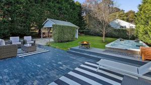 eine Terrasse mit Pool und Stühlen und einer Feuerstelle in der Unterkunft Dove Cottage in Bundanoon