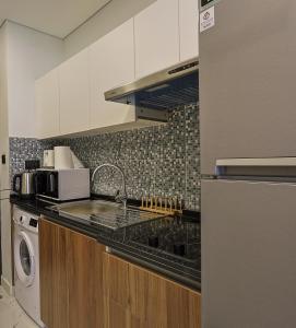 a kitchen with a sink and a washing machine at Masdar Modern Studio in Abu Dhabi