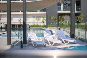 a group of chairs sitting next to a swimming pool at Masdar Modern Studio in Abu Dhabi