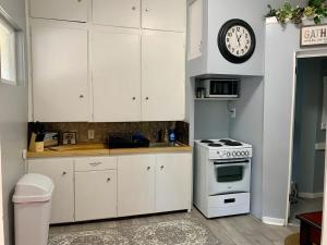une cuisine avec des armoires blanches et une horloge au mur dans l'établissement Beautiful Victorian Apartment, à Bay City