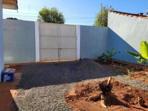 een achtertuin met een hek en een grinderf bij Casa com 2 quartos no Aero Rancho in Campo Grande +3 foto's