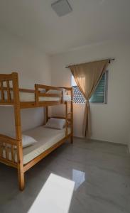 ein Schlafzimmer mit zwei Etagenbetten und einem Fenster in der Unterkunft Casa completa em Praia Grande, 500 metros da praia in Praia Grande