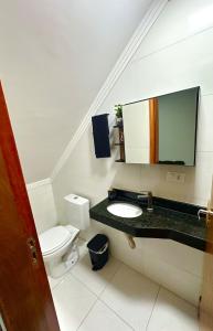 ein Badezimmer mit Toilette, Waschbecken und Spiegel in der Unterkunft Casa completa em Praia Grande, 500 metros da praia in Praia Grande