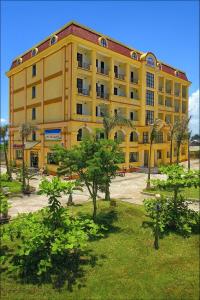 a yellow building with palm trees in front of it at Cửa Đại Beach Hotel in Hoi An