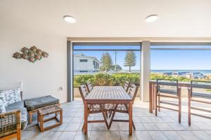 a dining room with a table and chairs and a view of the ocean at Sea Esta - Lennox Head in Lennox Head