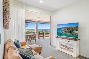 a living room with a couch and a tv at Sea Esta - Lennox Head in Lennox Head +9 photos