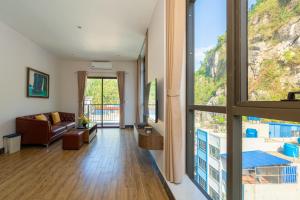a living room with a couch and a large window at Viet Hoa Hotel & Residence Cat Ba - Rooftop Pool in Cat Ba