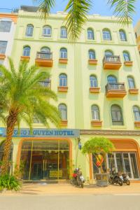 a large yellow building with a palm tree in front of it at Hưng Nguyễn Hotel in Ha Long