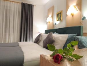 ein Hotelzimmer mit einem Bett und einer Blume auf einem Tisch in der Unterkunft RATSSCHÄNKE Südheide in Gifhorn