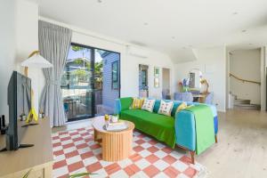 a living room with a green couch and a table at Lovely 3-BR Home in Long Bay Near Beaches & Albany in Auckland