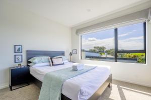 a bedroom with two beds and a large window at Lovely 3-BR Home in Long Bay Near Beaches & Albany in Auckland