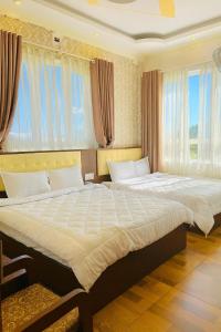 two beds in a bedroom with two windows at Bình Dương Đà Lạt Hotel in Da Lat