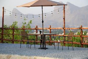 Una mesa y sillas con una sombrilla en un patio. en Alreef Cave, en Bahlāʼ
