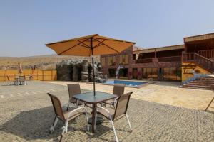 Una mesa y sillas con una sombrilla en un patio. en Alreef Cave, en Bahlāʼ