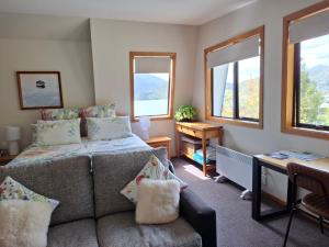 a bedroom with a couch and a bed with windows at Channel View Havelock in Havelock +6 photos