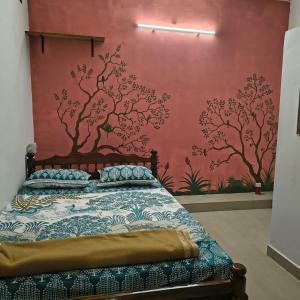 une chambre avec un lit avec un mur rouge dans l'établissement Thamara Auroville Homestay, à Pondichéry