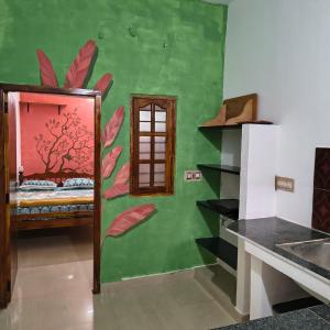 une chambre avec un lit dont le mur est orné d'un arbre. dans l'établissement Thamara Auroville Homestay, à Pondichéry
