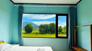 a bedroom with a window with a view of a field at sokxay guesthouse in Vang Vieng