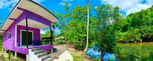 a pink house with stairs next to a body of water at Ari homestay in Ko Kood
