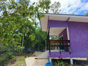 a purple house with a porch and a tree at Ari homestay in Ko Kood