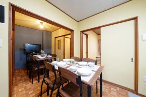 ein Esszimmer mit Tisch und Stühlen und einem Fernseher in der Unterkunft 5 minutes on foot from the station, 20 minutes by train to Nagoya station, and it is a detached house, so families can use it with peace of mind! in Nagoya
