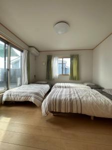 een slaapkamer met twee bedden en een raam bij 波音ハウス in Yugawara