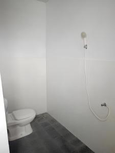 ブナケンにあるNovita Homestayのトイレとシャワー付きの白いバスルーム