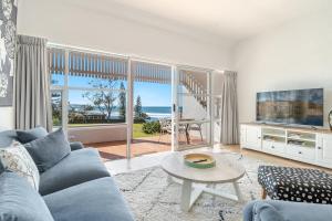 a living room with a blue couch and a view of the ocean at Quarterdeck Unit 2 - Lennox Head in Lennox Head