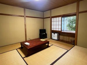 a room with a table and a television in it at Guesthouse PAW in Nagano