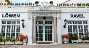 a white facade of a hotel with flowers in front at Löwen Hotel in Offenbach