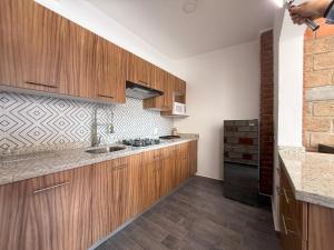 a kitchen with wooden cabinets and a sink at Rancho Valsan Cabaña El Tiro in El Oro de Hidalgo