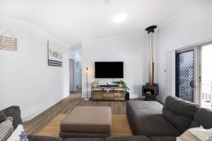 a living room with a couch and a flat screen tv at Conjola Escapes in Green Island