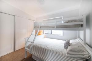 a white bedroom with a bunk bed and a window at Conjola Escapes in Green Island