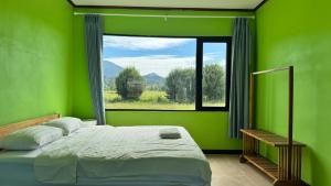 a green bedroom with a bed and a window at sokxay guesthouse in Vang Vieng