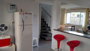 a kitchen with two red stools and a white refrigerator at Casa Matinhos Caioba Parana in Matinhos +20 photos