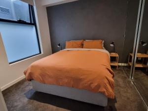 a bedroom with a bed with an orange comforter and a window at It's Melbourne - by the Beach! in Melbourne