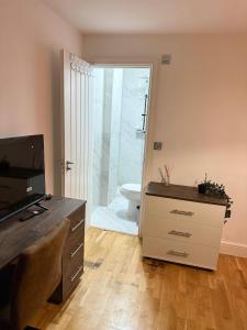 ein Badezimmer mit Toilette und eine Kommode mit Fernseher in der Unterkunft Finchley Unique home in Finchley