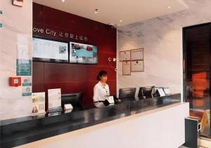 une femme qui se tient au guichet d'un magasin dans l'établissement City Comfort Inn Zhuhai Jinwan Hangkong Xincheng, à Baigaonongchang