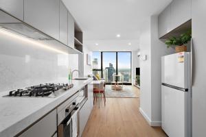 a white kitchen with a stove and a refrigerator at Home in the Sky 2BR Apt with City and River View in Melbourne