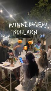 a group of people sitting at a table with a cell phone at winnerview ll Resort Kohlarn in Ko Larn