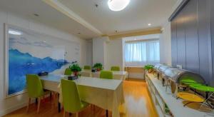 une grande chambre avec des tables et des chaises vertes dans l'établissement Shell Hotel Huaibei Jinying Plaza Long Distance Bus Station, à Huaibei