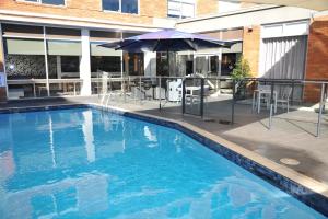 - une piscine avec un parasol, des tables et des chaises dans l'établissement Royal Pacific Hotel, à Sydney