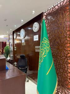 a green umbrella in an office with clocks on a wall at فندق الروضة قريب من حفلات توصيل للحرم مجاناً in Al Khansāk
