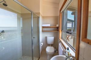 a bathroom with a shower and a toilet and a sink at Moonrise Cove in Pelican Lagoon +23 photos