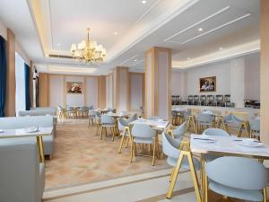 une salle à manger avec des tables et des chaises blanches dans l'établissement Vienna Hotel Guangdong Shantou Chaoyang Heping, à Heping