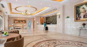 une femme traverse une grande pièce avec un hall dans l'établissement Vienna Hotel Guangdong Boluo Fu Mountain Scenic Spot, à Changning