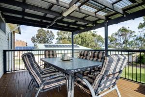 a patio with a table and chairs on a deck at Perfect family holiday in Berrara