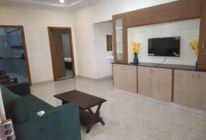 a living room with a tv and a couch and a table at Hotel O Pinaka Grand A Luxurious Homestay in Narasingāpuram