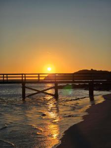 a sunset over the beach with a pier at Blon Homestay 