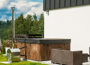 a patio with two wicker chairs and a television at KASZUBY - Domki na Szczycie - jeden na ogrodzonej działce z balia jacuzzi na wyłączność in Krzeszna